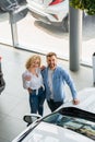 Happy couple near their new car in dealership. Royalty Free Stock Photo