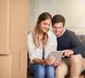 Happy couple, new home and browsing with tablet by boxes for moving in, renovation or relocation. Young man and woman Royalty Free Stock Photo