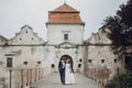 Happy couple of newlyweds walking near castle, fairytale wedding moment beautiful bride and groom hug near ancient castle entrance