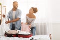 Happy couple packing clothes into suitcase, preparing for honeymoon Royalty Free Stock Photo