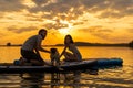 Happy couple paddle boarding at lake during sunset together with pug dog. active family tourism