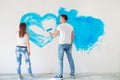 Happy couple painting walls in their new house ready for living together. Royalty Free Stock Photo