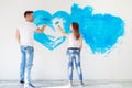 Happy couple painting walls in their new house ready for living together. Royalty Free Stock Photo