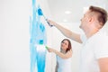 Happy couple painting walls in their new house ready for living together. Royalty Free Stock Photo