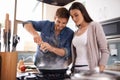 Happy couple, pan and cooking together in the kitchen with food or healthy ingredients for dinner at home. Man and woman Royalty Free Stock Photo