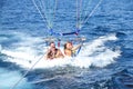 Happy couple parasailing on beach in summer. two people under parachute lowered into sea for fun Royalty Free Stock Photo