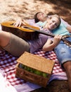 Happy couple, picnic and playing guitar for love, romance or music in outdoor bonding, fun or relaxing together in Royalty Free Stock Photo