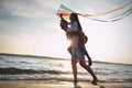 Happy couple playing with kite on beach near sea at sunset. Spending time in nature Royalty Free Stock Photo