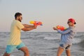 Happy couple playing with water guns at sunset