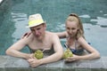 Happy couple in the pool with a coconut cocktail
