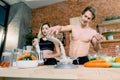 Happy couple preparing dinner, guy puts rice on weight, in loft kitchen at home. Family cooking healthy food. Royalty Free Stock Photo