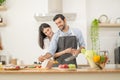 Happy couple preparing food at home, young couple cutting vegetables together at kitchen counter