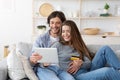 Happy couple purchasing online, holding credit card and digital tablet