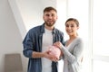 Happy couple putting coin into piggy bank indoors. Money savings concept Royalty Free Stock Photo