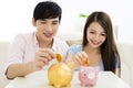 Happy couple putting coin into piggy bank