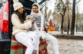 Happy couple holding a fluffy rabbit in the back of car with Christmas gift box in winter forest. Royalty Free Stock Photo