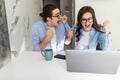 Happy young couple with raised arms of win celebrate looking on laptop in kitchen Royalty Free Stock Photo