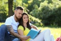 Happy couple reading book in park on spring day Royalty Free Stock Photo