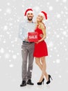 Happy couple with red sale sign over snow Royalty Free Stock Photo