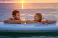 Happy couple relax on the paddle board at sunset