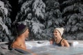 Happy couple relaxing in outdoor hot tub at winter with snowy trees in background. spa resort Royalty Free Stock Photo