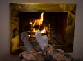 Happy couple relaxing under blanket by the fireplace warming up feet in woolen socks Royalty Free Stock Photo