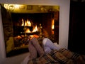 Happy couple relaxing under blanket by the fireplace warming up feet in woolen socks Royalty Free Stock Photo