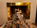 Happy couple relaxing under blanket by the fireplace warming up feet in woolen socks Royalty Free Stock Photo