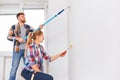 Happy couple renovating their new home together using rollers on white wall Royalty Free Stock Photo