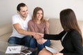Happy couple renters owners shaking hands with real estate agent