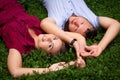 Happy couple resting in a park on green grass. Slow Motion. Smiling man and woman talking, enjoying a warm summer day Royalty Free Stock Photo