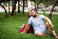 Happy couple resting in a park on green grass. Slow motion. Smiling man and woman talking while enjoying a warm summer Royalty Free Stock Photo