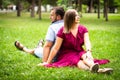 Happy couple resting in a park on green grass. Slow motion. Smiling man and woman talking while enjoying a warm summer Royalty Free Stock Photo