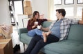 Happy Couple Resting On Sofa Surrounded By Boxes In New Home On Moving Day Royalty Free Stock Photo