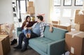 Happy Couple Resting On Sofa Surrounded By Boxes In New Home On Moving Day Royalty Free Stock Photo