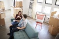 Happy Couple Resting On Sofa Surrounded By Boxes In New Home On Moving Day Royalty Free Stock Photo