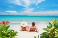 Happy couple resting on tropical beach on summer sunny day on background of beautiful blue sky and turquoise sea. Royalty Free Stock Photo