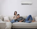 Happy couple resting under air conditioner on white wall at home Royalty Free Stock Photo