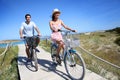 Happy couple riding bikes on the coast