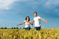 Happy couple running over grainfield