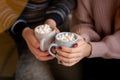 Happy couple`s hands holding hot cups with hot drinks with marshmallow Royalty Free Stock Photo