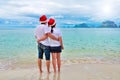 Happy couple in Santa hats relaxing on tropical sandy beach near sea, Christmas and New Year holiday vacation Royalty Free Stock Photo