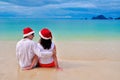 Happy couple in Santa hats relaxing on tropical sandy beach near sea, Christmas and New Year holiday vacation Royalty Free Stock Photo