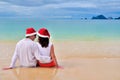 Happy couple in Santa hats relaxing on tropical sandy beach near sea, Christmas and New Year holiday vacation Royalty Free Stock Photo