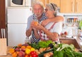 Happy couple of senior people drinking the juice fruit just made. Wooden table with a large group of colorful fruits and Royalty Free Stock Photo