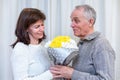 Happy couple seniors celebrate Valentine's Day. Man gives woman a favorite bouquet of flowers. Romantic relationships