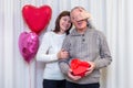 Happy couple seniors celebrate Valentine& x27;s Day. Woman closes man& x27;s eyes and gives him gift. Romantic relationships, love