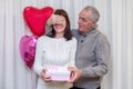 Happy couple seniors celebrate Valentine& x27;s Day. Man closes the woman& x27;s eyes and gives her gift. Romantic relationships