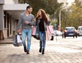 Happy couple, shopping bags and walking in city together for fashion, gift or buying in the outdoors. Man and woman in Royalty Free Stock Photo