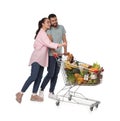 Happy couple with shopping cart full of groceries on white background Royalty Free Stock Photo